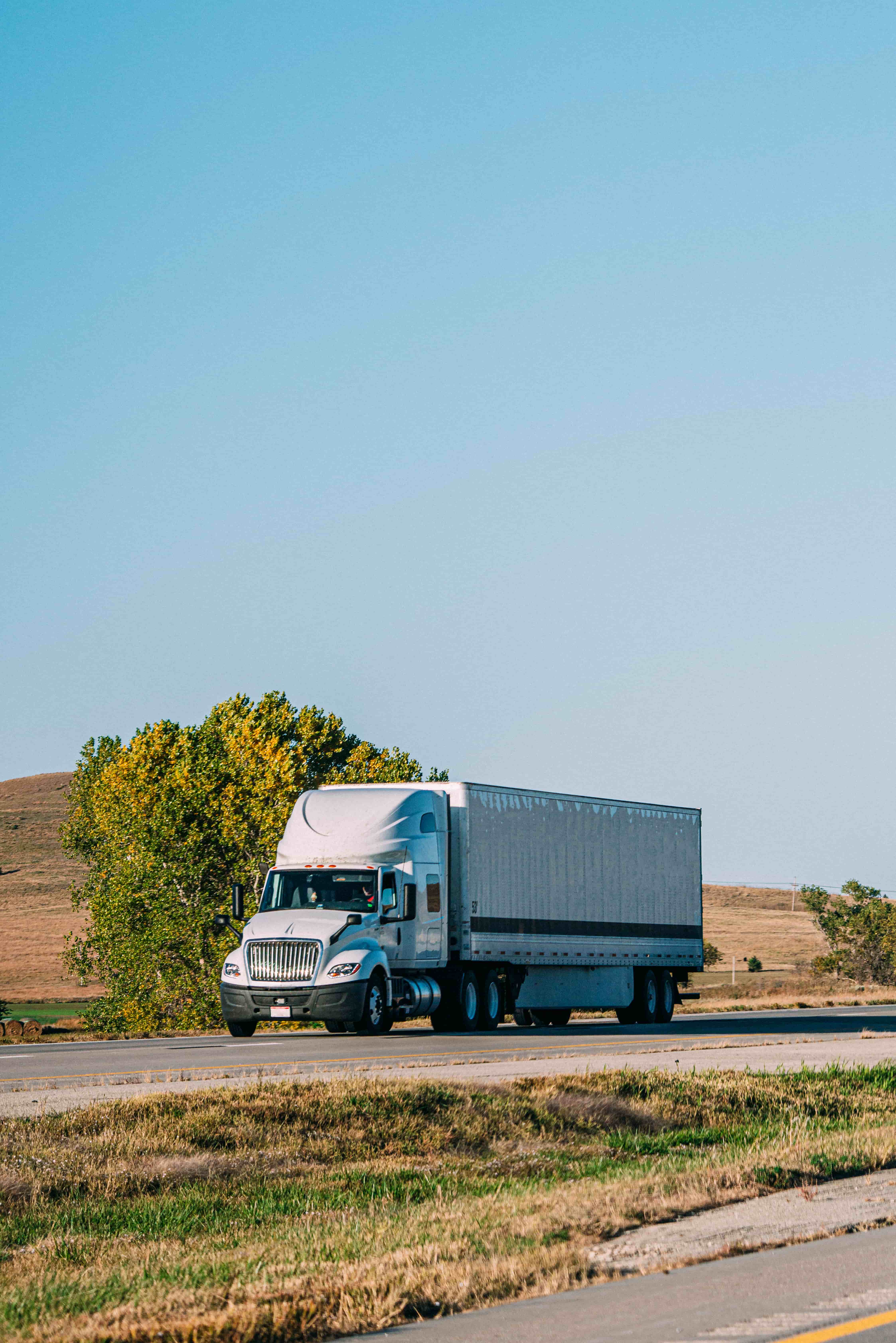 A Sacred Earth Produce refrigerated delivery truck on a sunny California road.